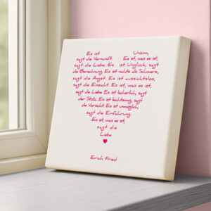 Leinwandbild Liebesgedicht Was es ist von Erich Fried in Weiss und Pink, an einer Wohnraum-Wand stehend