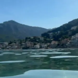 Blick vom Wasser aus auf die Bucht von Port de Sóller mit den Häusern am Hang und den Bergen der Tramuntana.