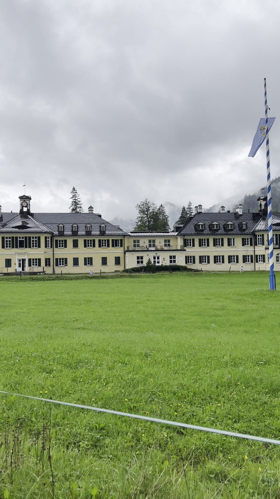 Wildbad Kreuth, the historic yellow main building above the Tegernsee with Bavarian maypole and mountain backdrop