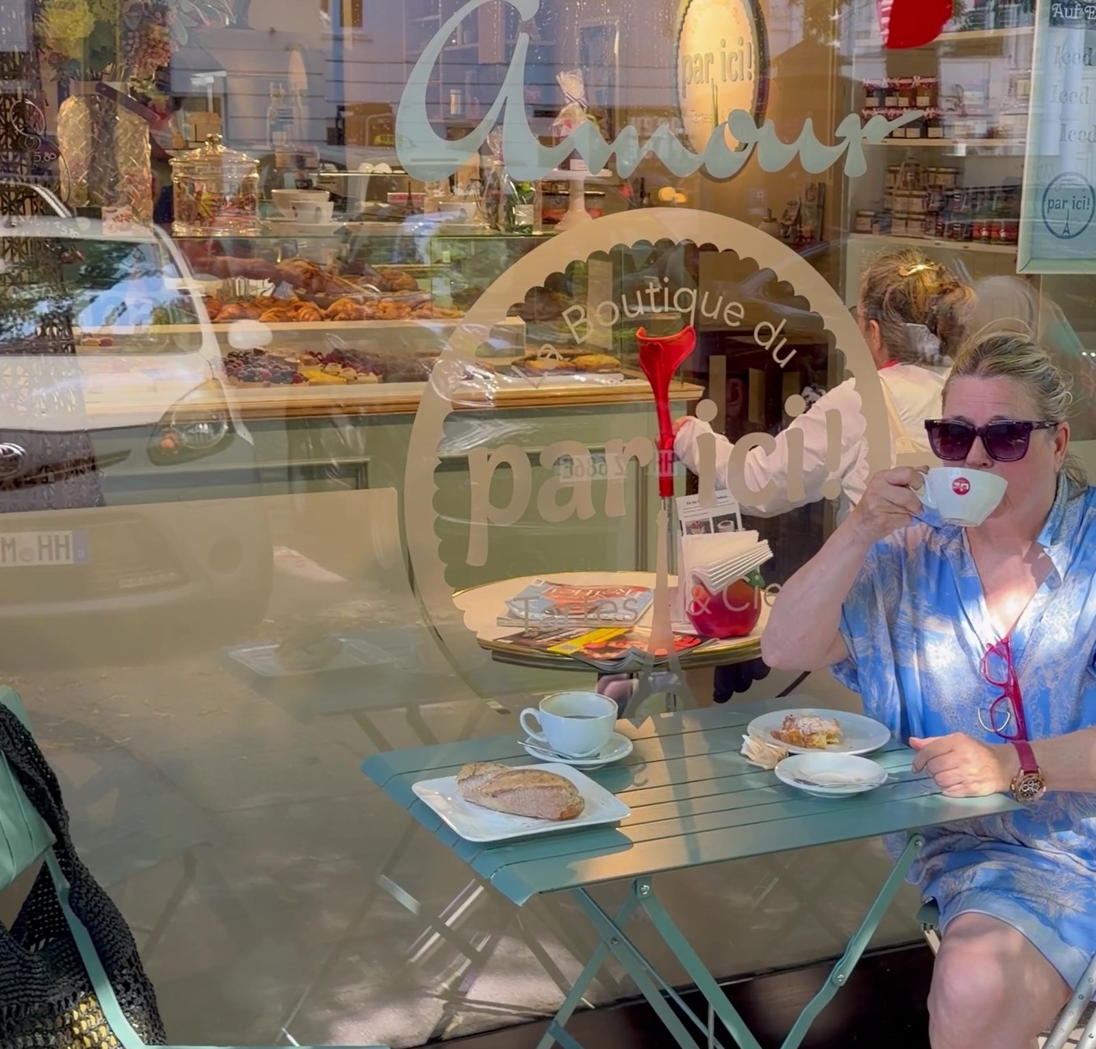 Café Crème am Bistrotisch vor dem par ici in Eimsbüttel, im Fenster der Schriftzug Amour