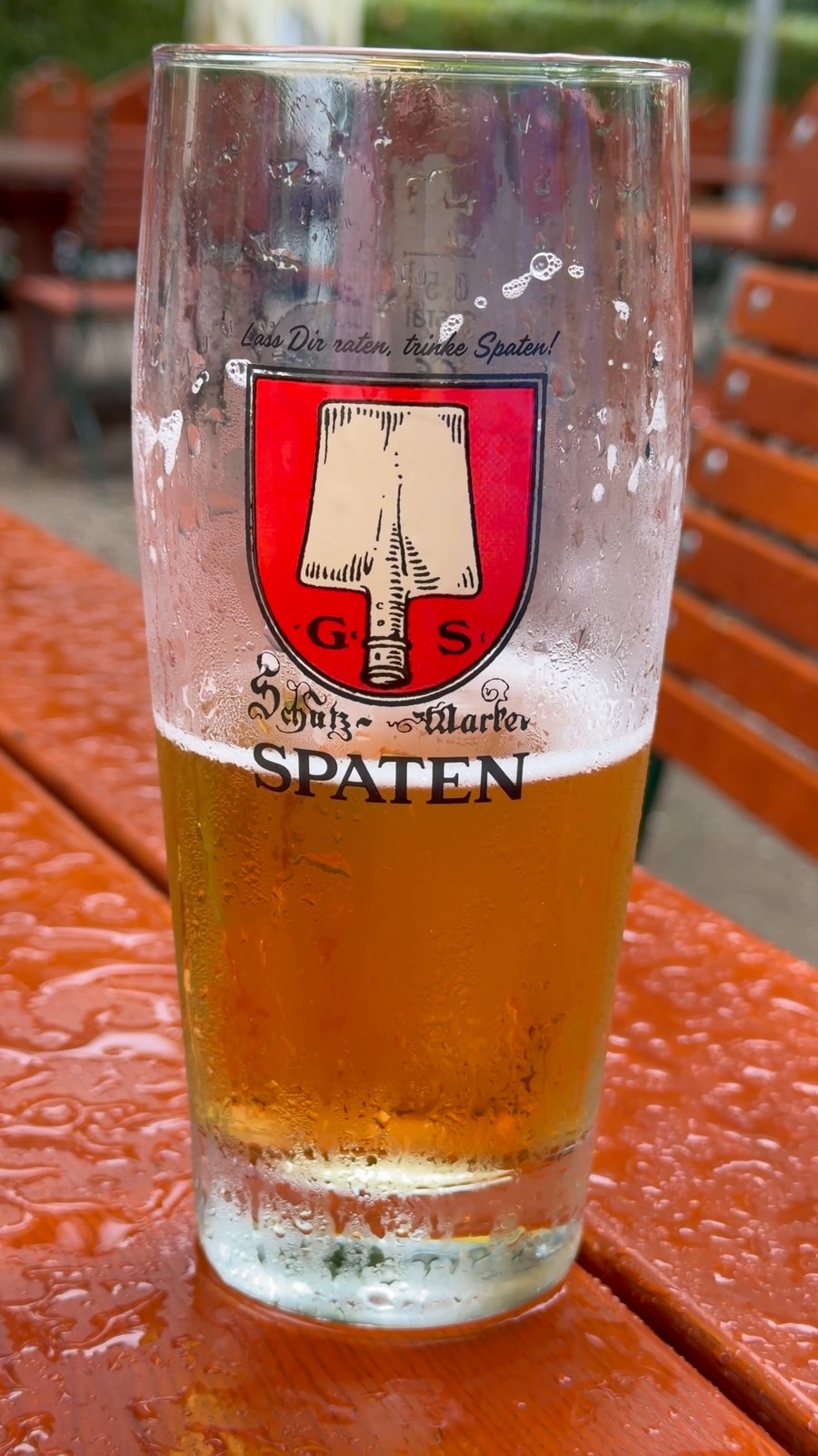 Glas Helles auf dem roten Biergartentisch der Emmeramsmühle in München