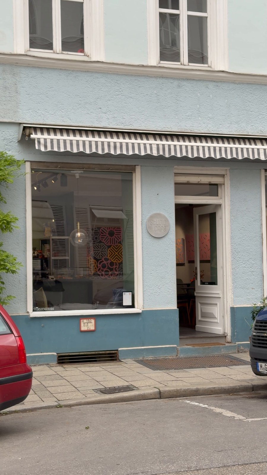 Studio Café in München mit mintblauer Fassade und gestreifter Markise
