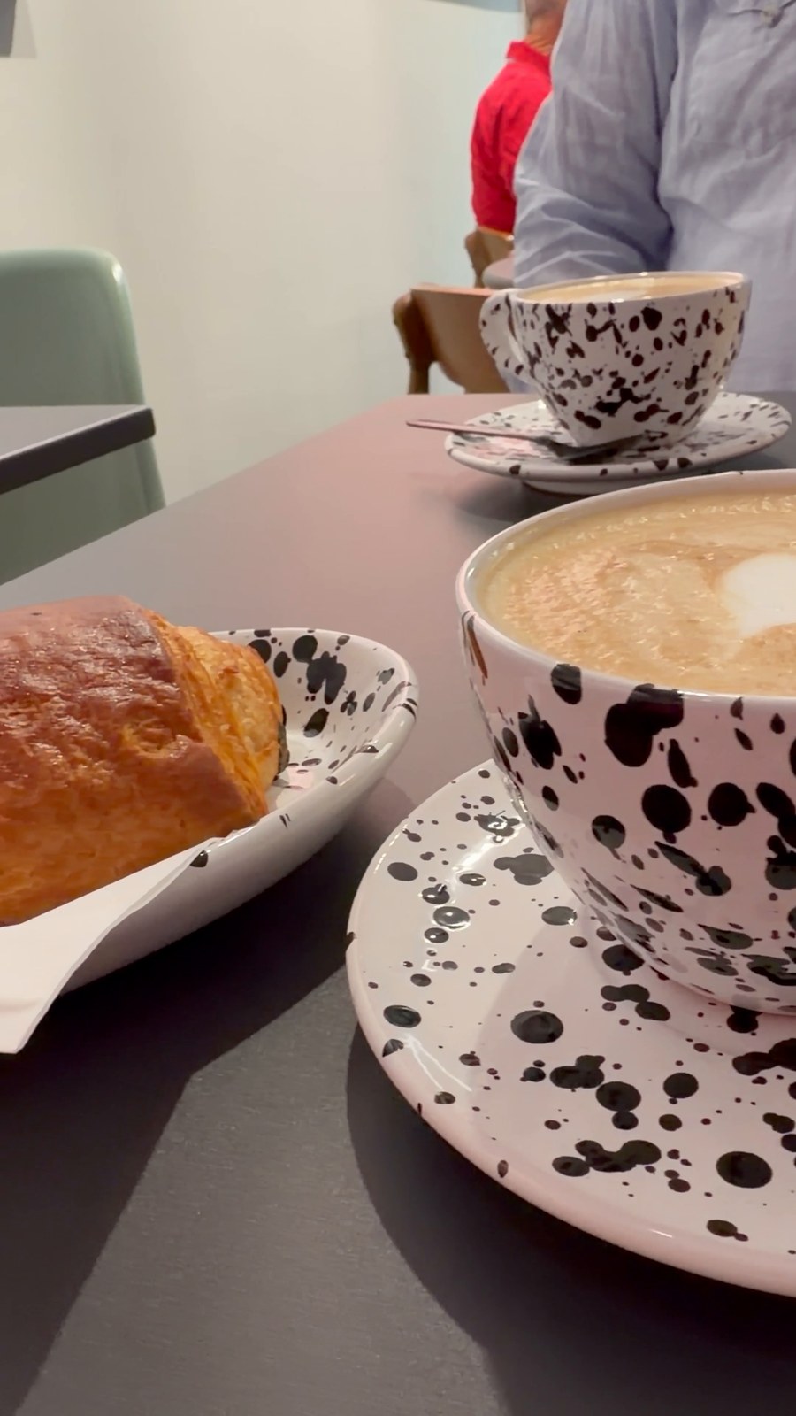 Pain au chocolat und Cappuccino auf gesprenkeltem Geschirr im Studio Café München