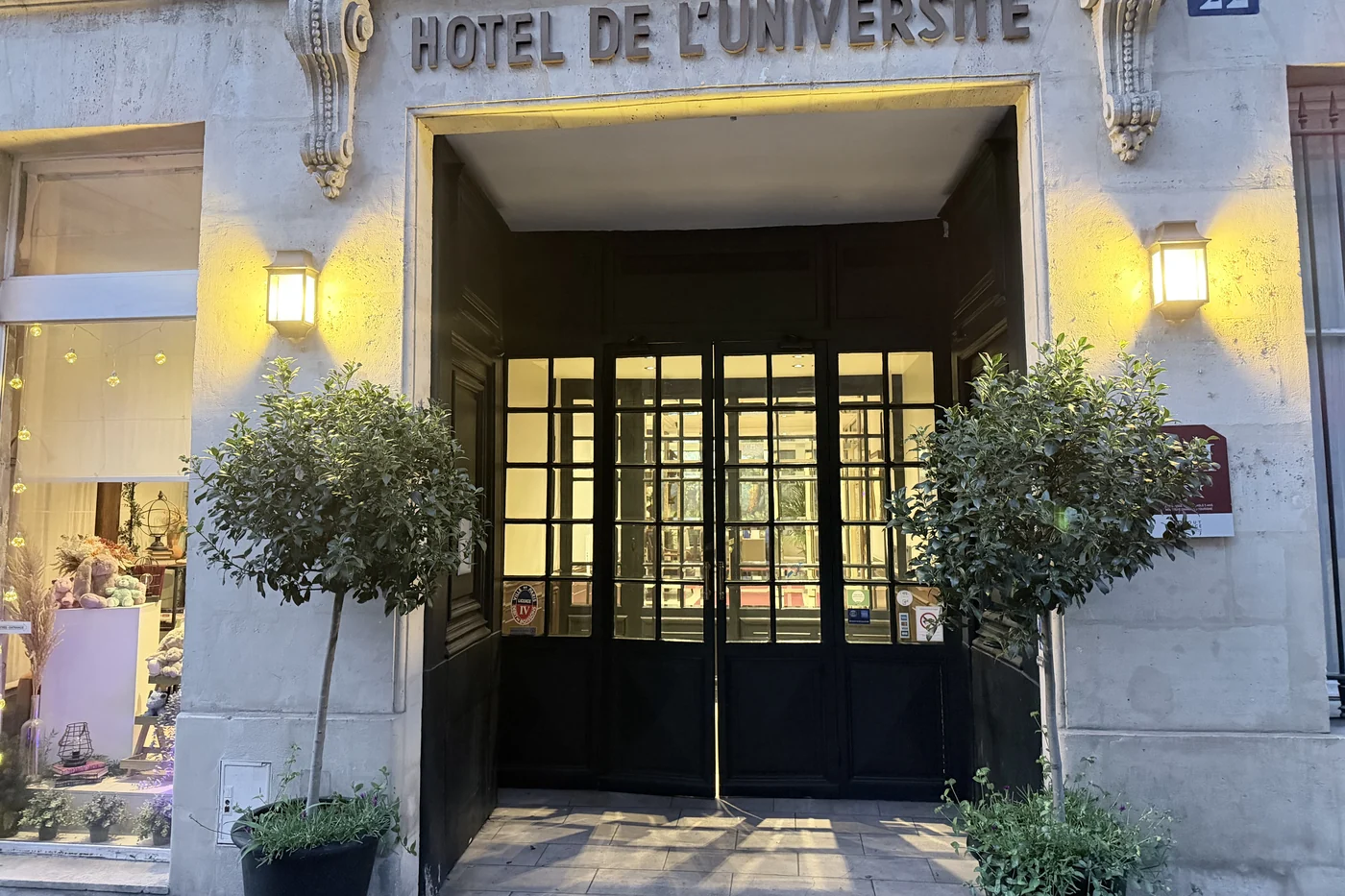 Eingang des Hôtel de l’Université in Paris mit Schriftzug über der Tür und zwei Bäumchen davor