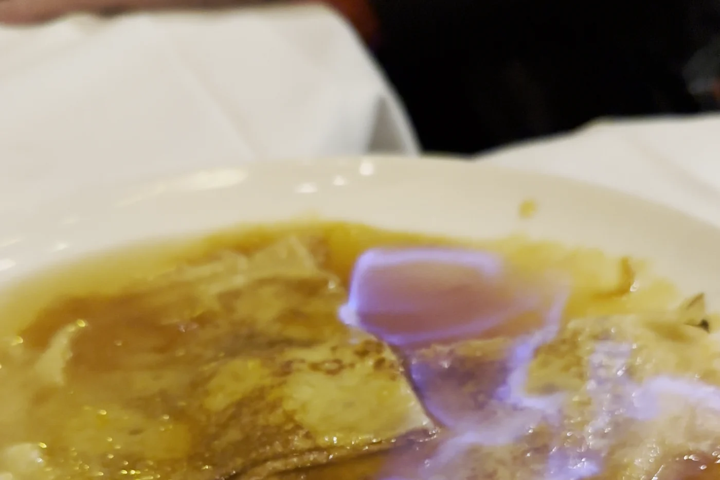Brennende Crêpe Suzette mit blauer Flamme auf dem Teller im Restaurant Les Antiquaires in Paris