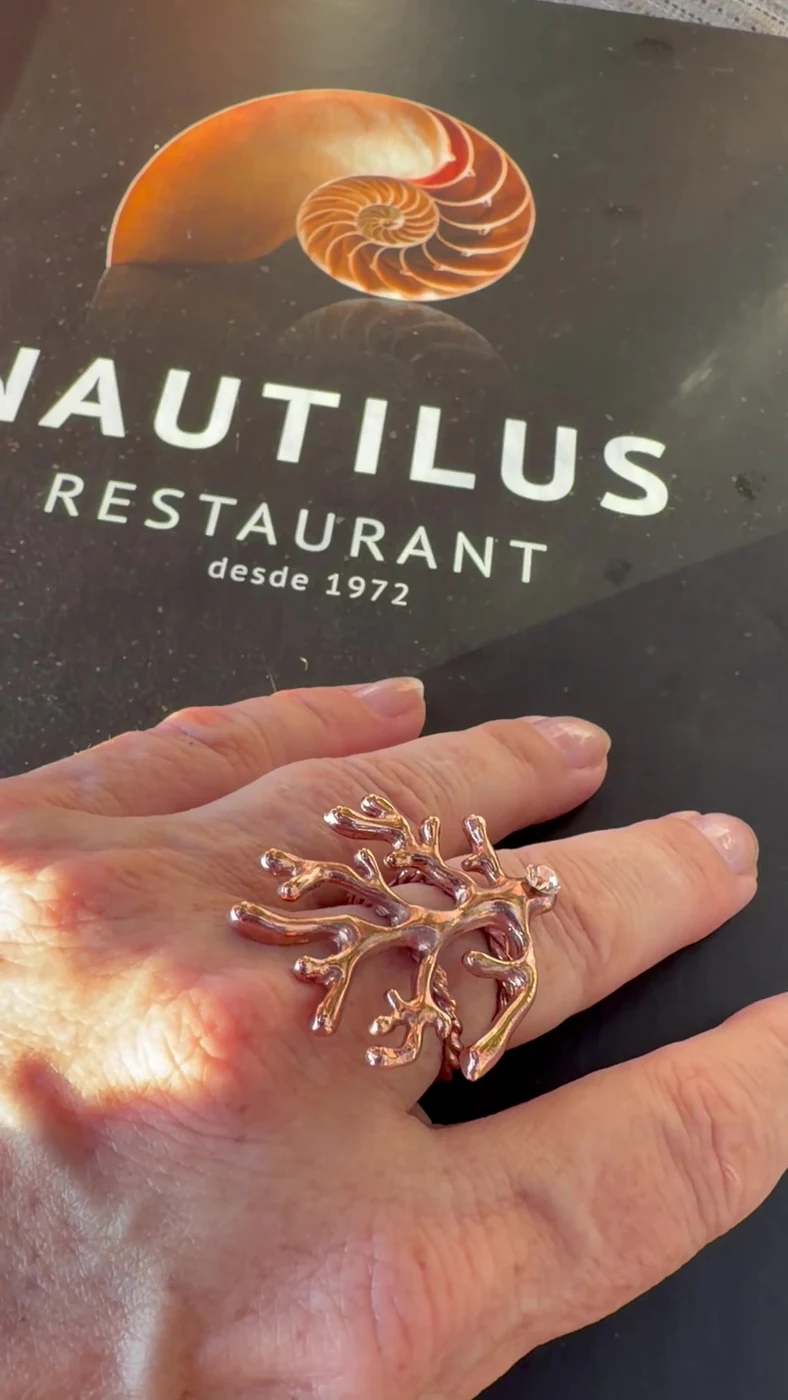 Hand wearing the Oceania ring by Ekaterini on the menu of the Nautilus restaurant in Port de Sóller.