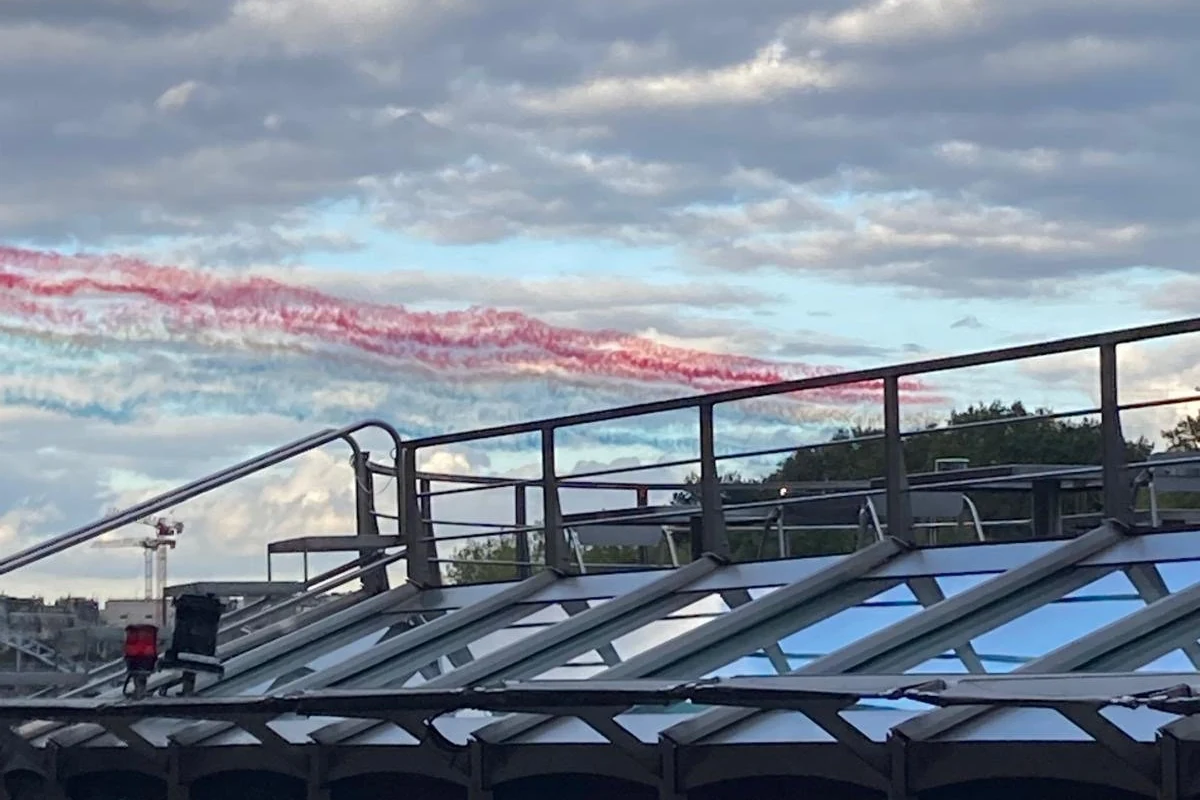 Blau-weiß-rote Rauchfahnen der Patrouille de France am Himmel über Paris, aufgenommen vom Deck an der Seine