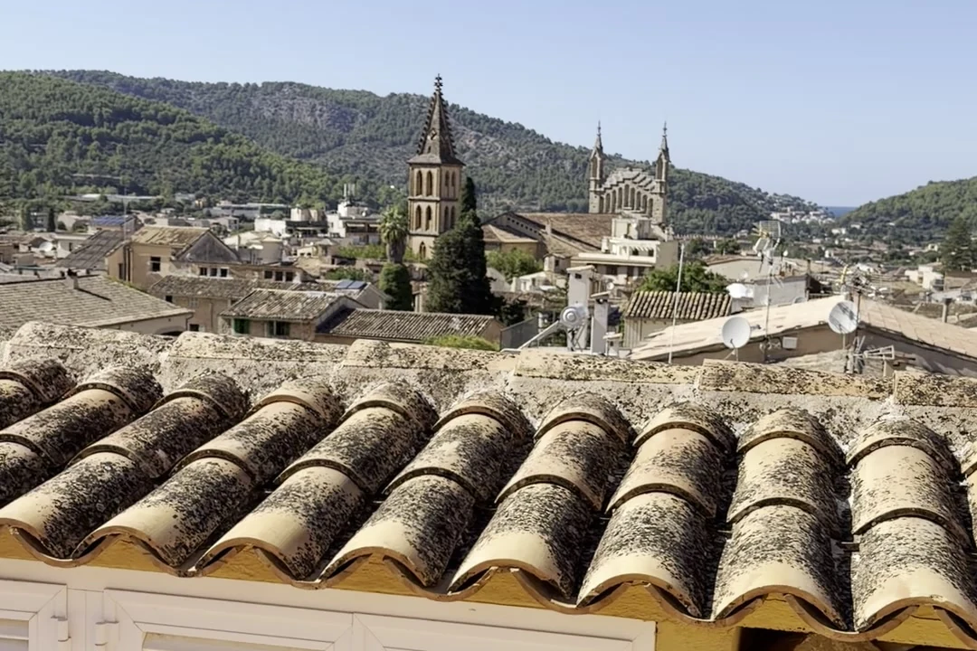 Blick über die Ziegeldächer von Sóller auf die Kirche Sant Bartomeu und die Berge dahinter.