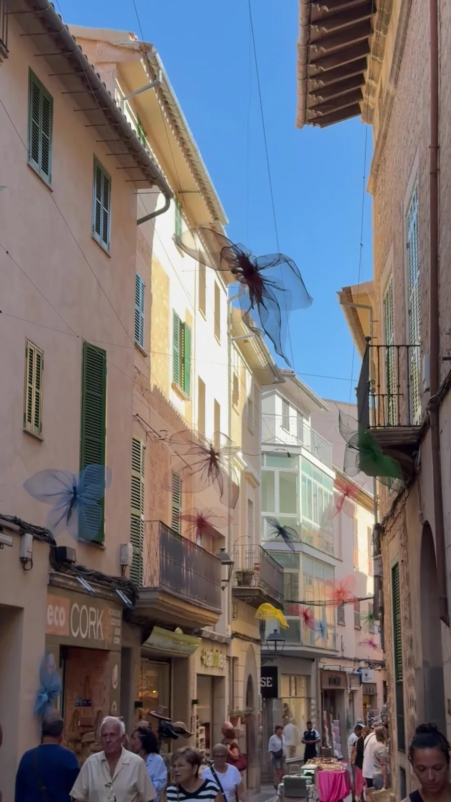 Gasse in Sóller mit durchsichtigen Stofflibellen in Türkis, Rot und Rosa über der Straße