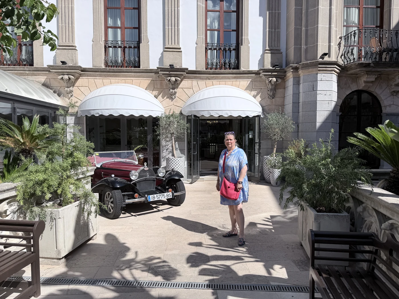 Corinna Gronau vor dem Gran Hotel Sóller, daneben ein Oldtimer vor der Fassade im Stil des katalanischen Modernisme.