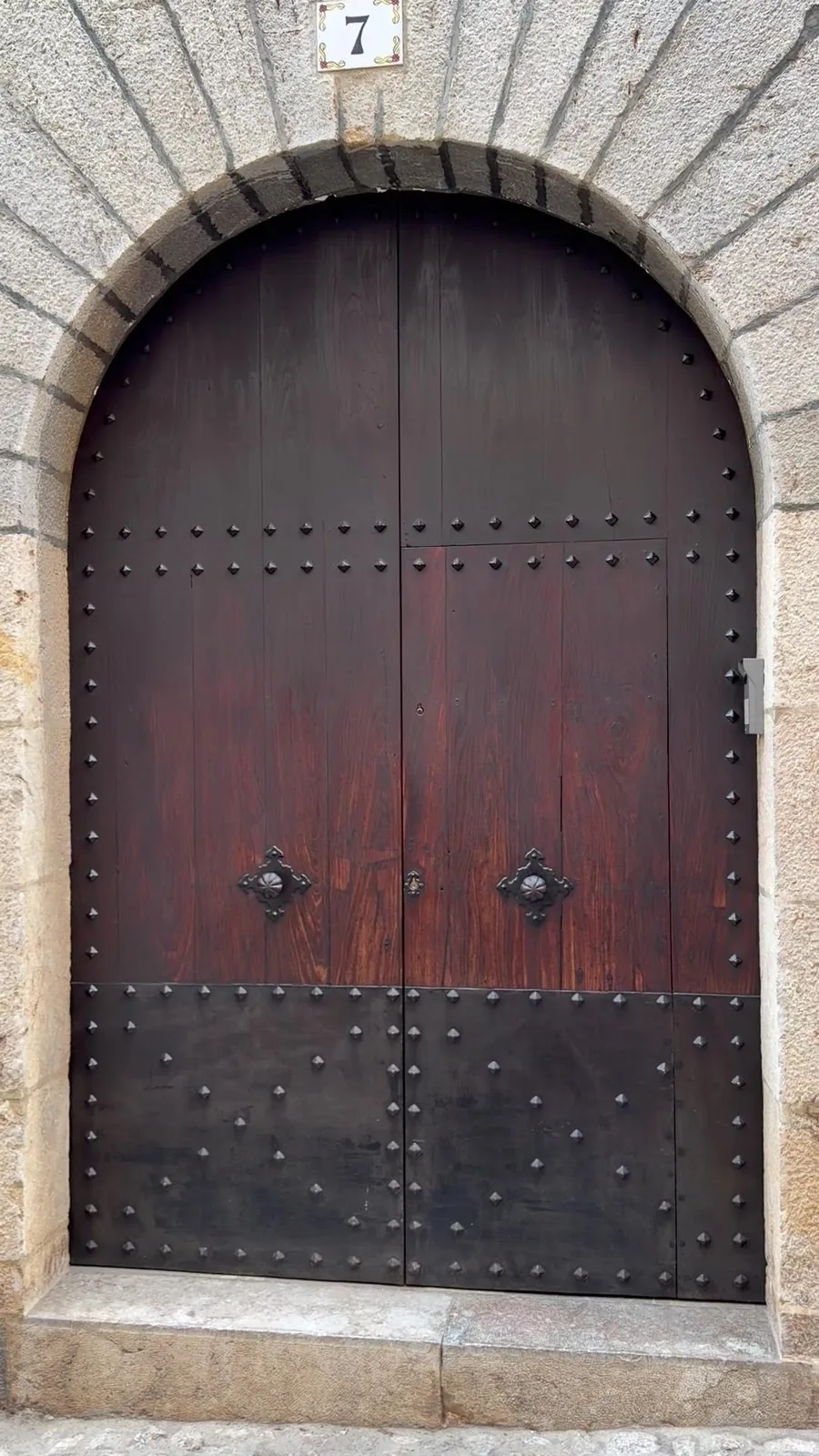Altes Rundbogenportal in Sóller aus dunklem Holz mit schweren Nagelbeschlägen und der Hausnummer 7