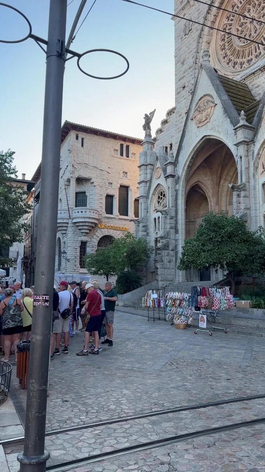 Kirche Sant Bartomeu in Sóller mit großer Rosette, davor Marktstände und die Gleise der Straßenbahn