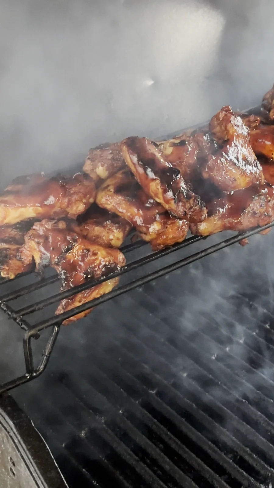 Glasierte Barbecue-Hähnchenteile auf dem Grillrost im Rauch beim Catering von Michelle Wong bei uns zu Hause in Hamburg
