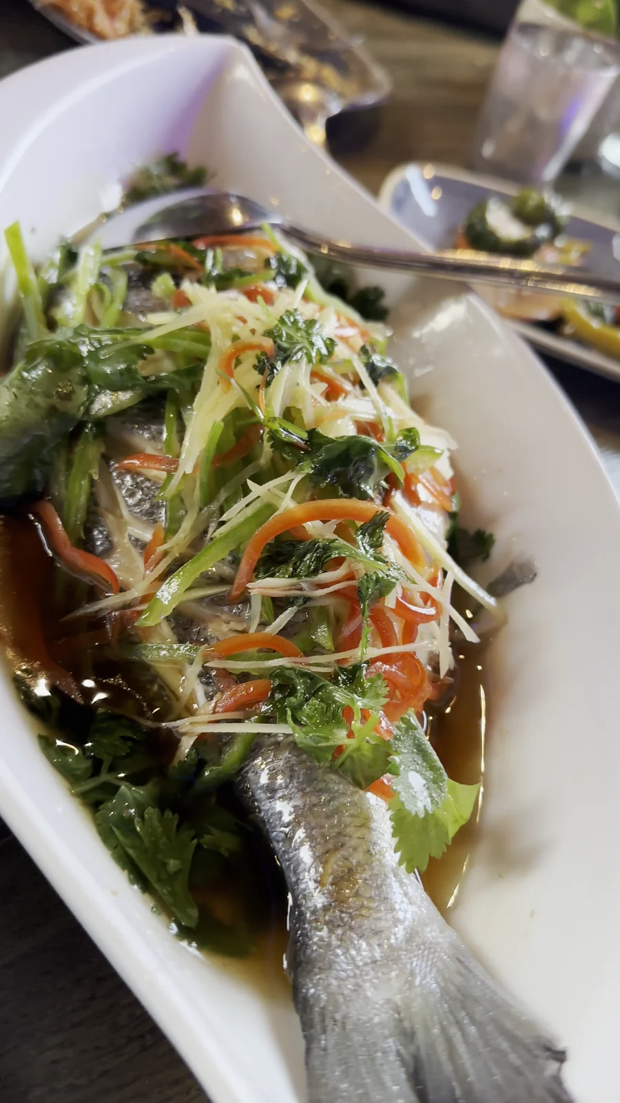 Ganzer gedämpfter Fisch mit Ingwer, Frühlingszwiebeln, Chili und Koriander in Sojasauce im Restaurant Wong Hamburg