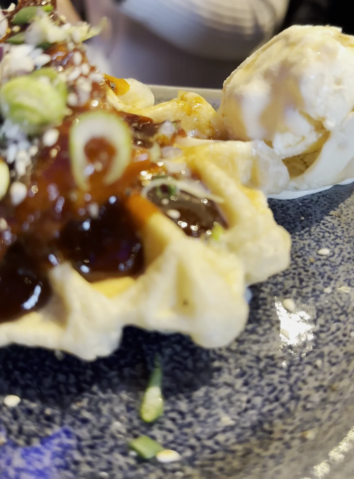 Korean Chicken auf einer Waffel mit einer Kugel Walnusseis auf einem Steinteller im Restaurant Wong Hamburg