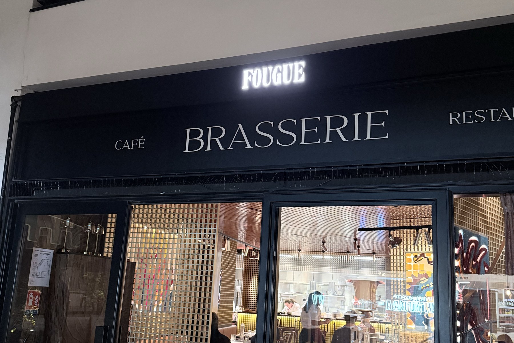Fassade der Brasserie Fougue in der Rue de Grenelle mit der Leuchtschrift FOUGUE über den Schriftzügen Café, Brasserie und Restaurant