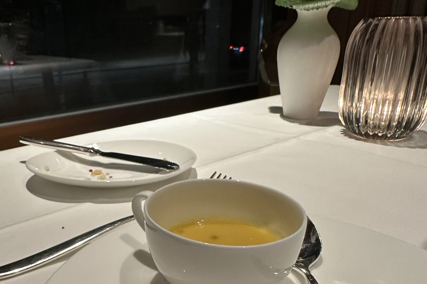 Eingedeckter Fenstertisch im Restaurant des Hotel Atlantic am Abend, eine kleine weiße Vase und ein geriffeltes Windlicht am Fenster.