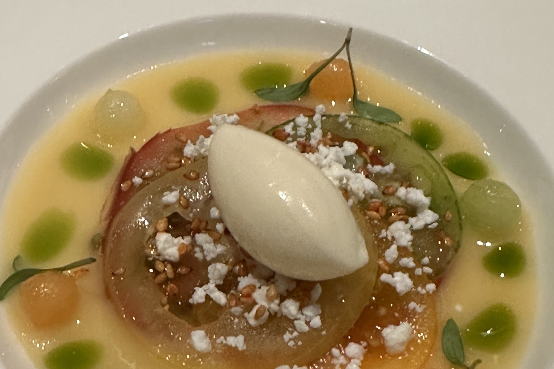 Tomatoes in every colour with dots of green oil, small spheres and a pale quenelle in the middle.