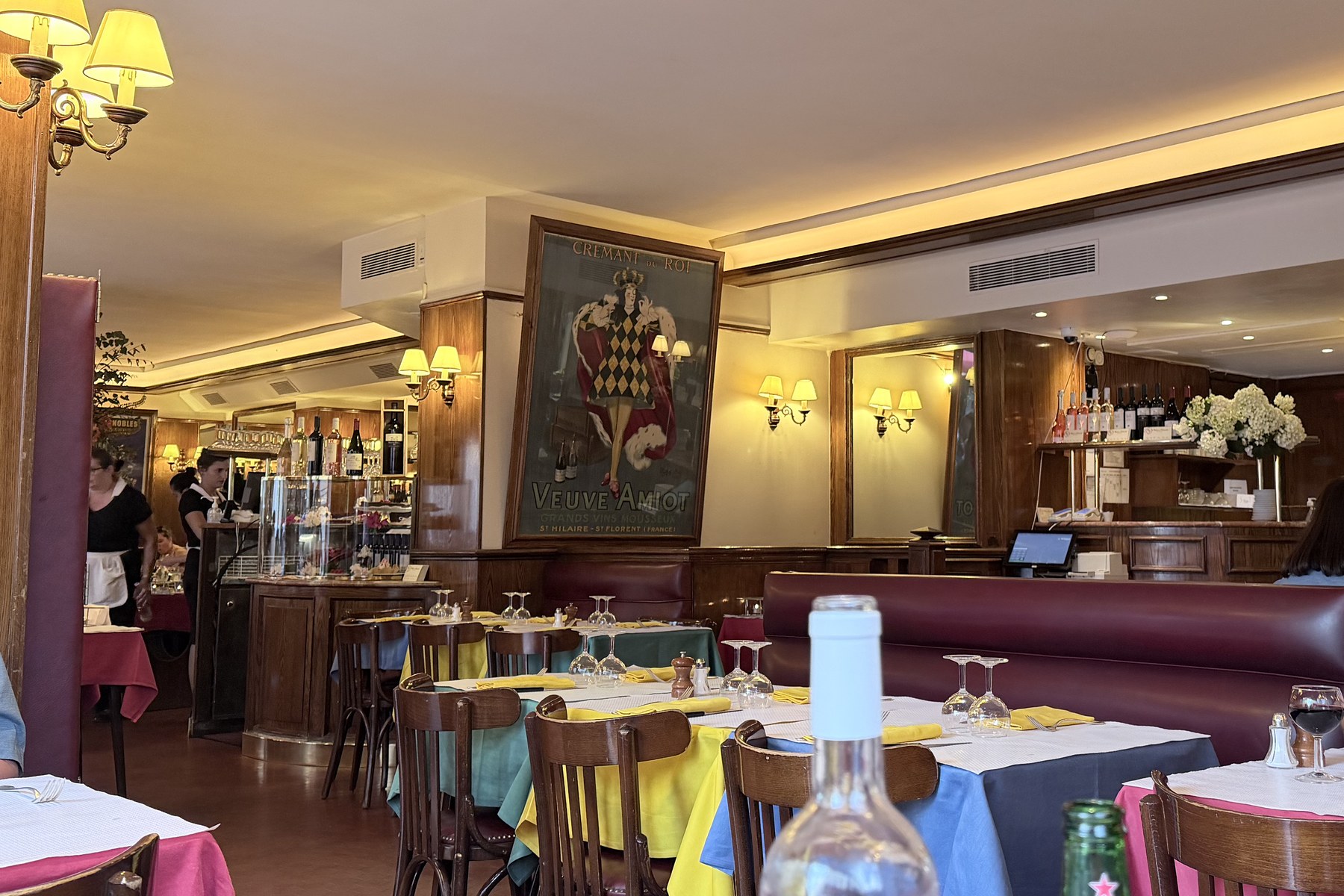 Gastraum des Relais de l'Entrecôte mit gelben und grünen Tischdecken, Bugholzstühlen und einer Flasche Château de Saurs auf dem Tisch