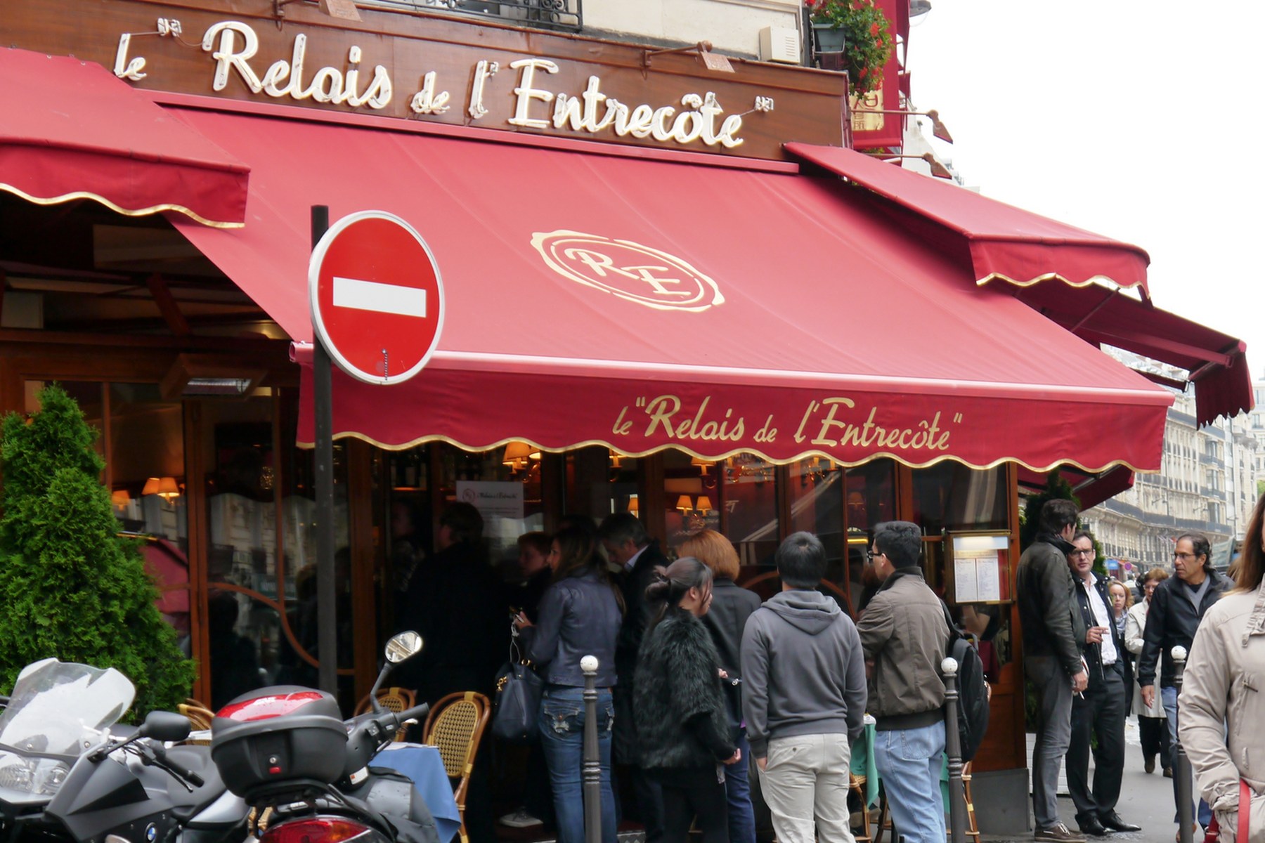 Rote Markise mit dem Schriftzug Le Relais de l'Entrecôte in der Rue Saint-Benoît in Paris, davor eine Warteschlange