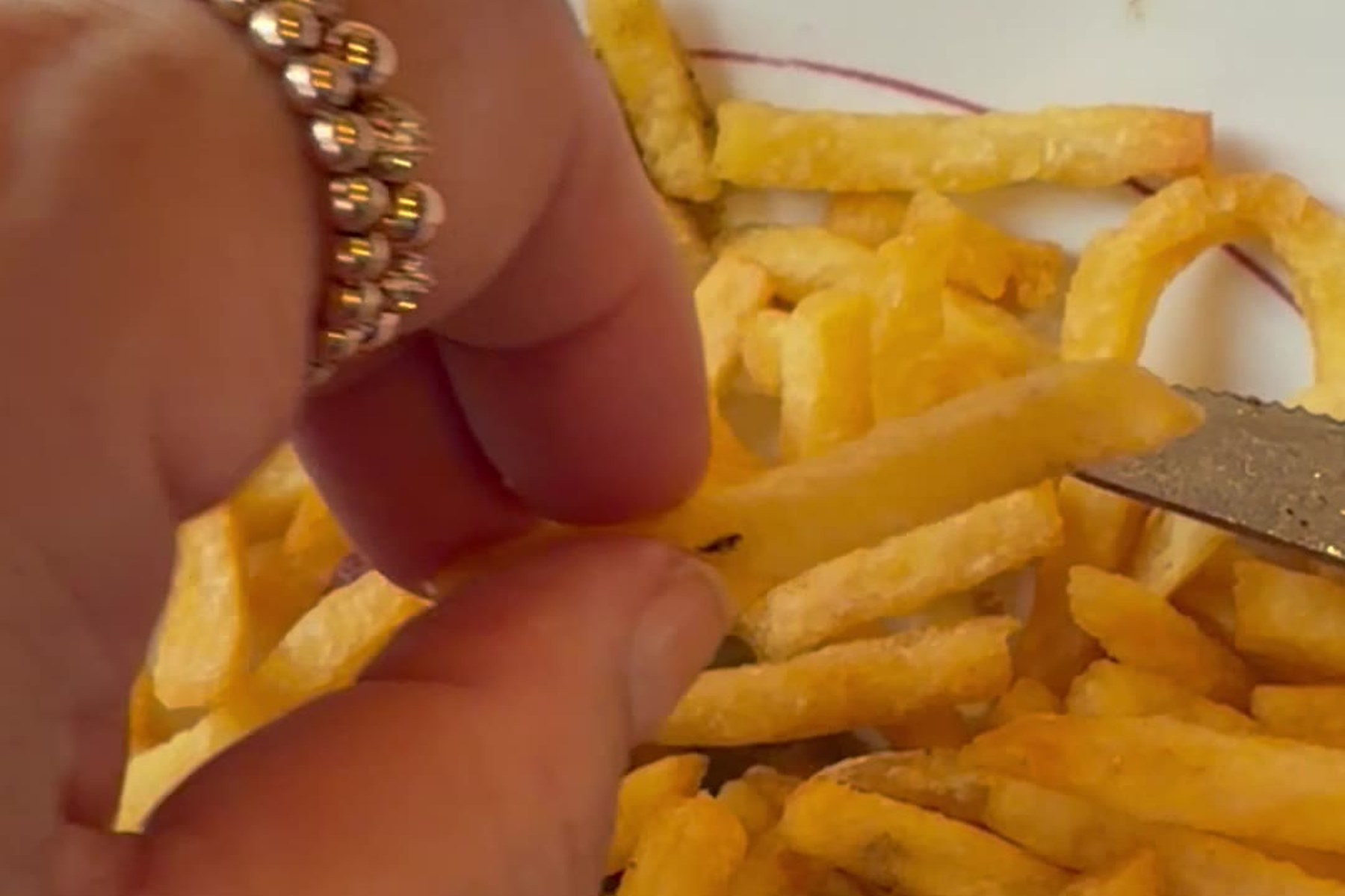 Hand greift eine Pommes allumette vom Teller mit Entrecôte und Kräutersauce