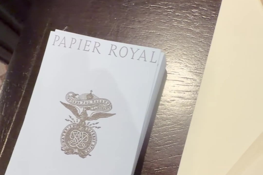 Hauskarte von Papier Royal mit geprägtem Wappen auf dem dunklen Holztresen