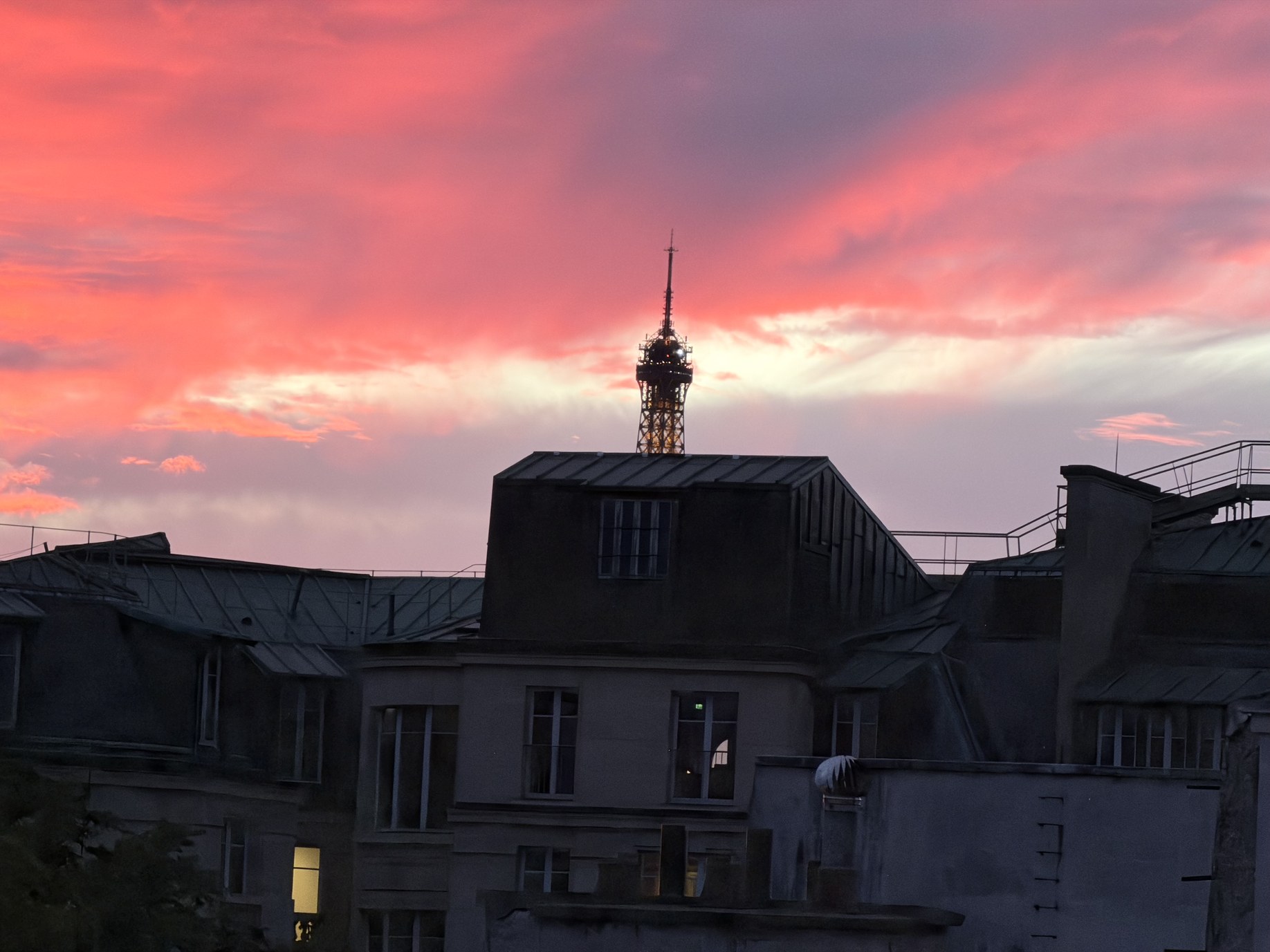 Red evening sky above the zinc roofs of Saint-Germain-des-Prés with the tip of the Eiffel Tower.